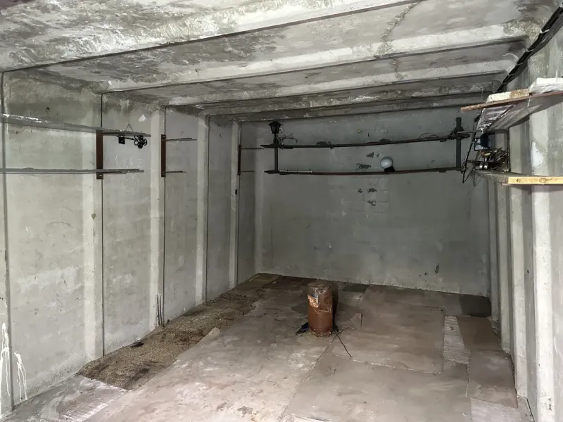 An empty concrete room with pipes and lighting, garage interior.