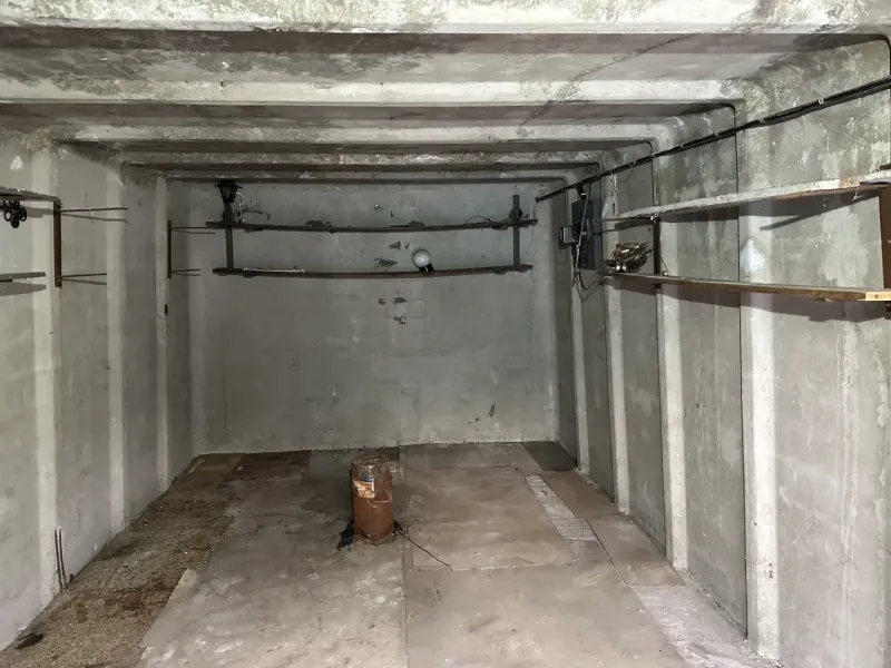 Empty concrete garage interior with shelves and lighting equipment.
