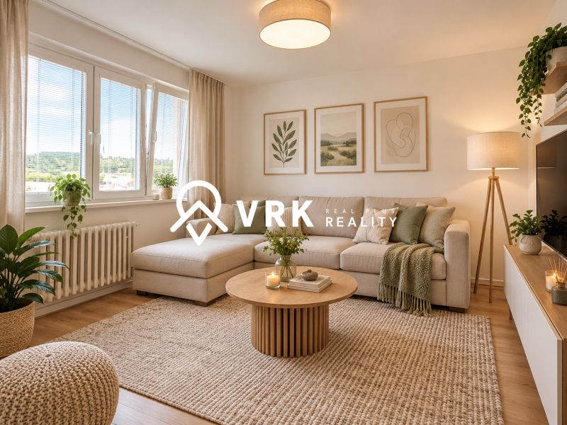 Living room in a two-room apartment with a sofa, plants, and wood-patterned flooring.