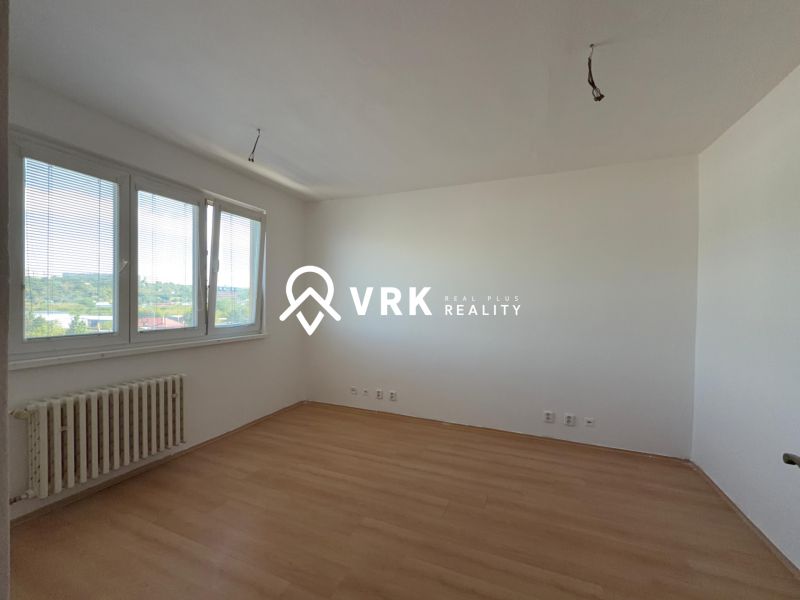 A room in a 2-room apartment with a wooden decor floor and a view from the window.