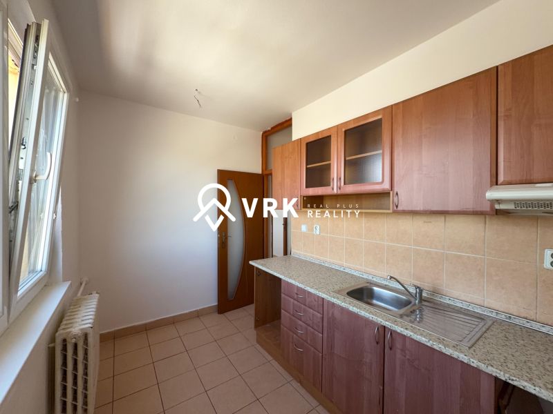 A kitchen in a 2-room apartment with ceramic tiles and wooden cabinets.