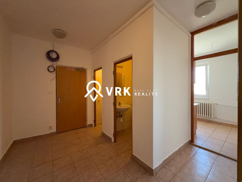 Interior of a 2-room apartment with tiles, bathroom on the left and room with a window on the right.