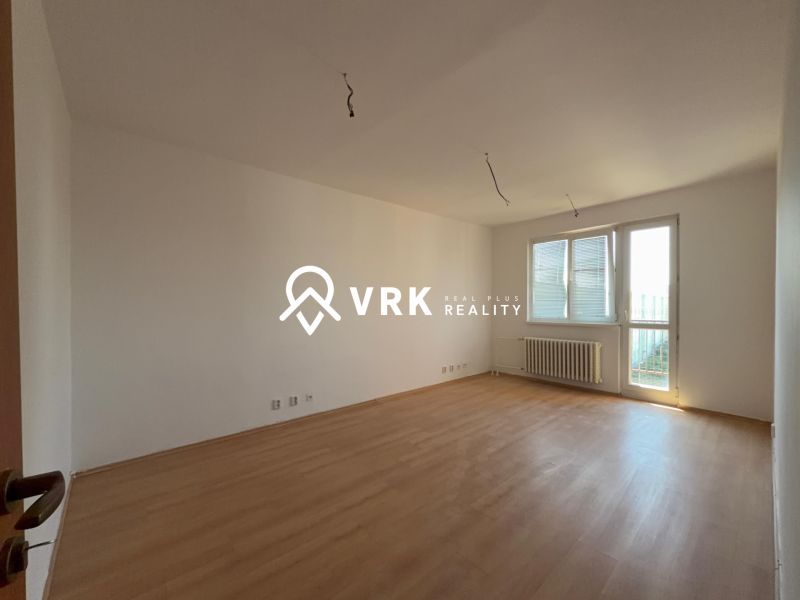 A spacious room with a wooden decor floor in a 2-room apartment.