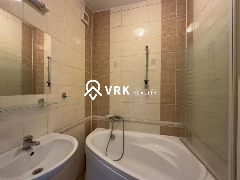 Bathroom in a 2-room apartment with a bathtub and a sink, light tiles.