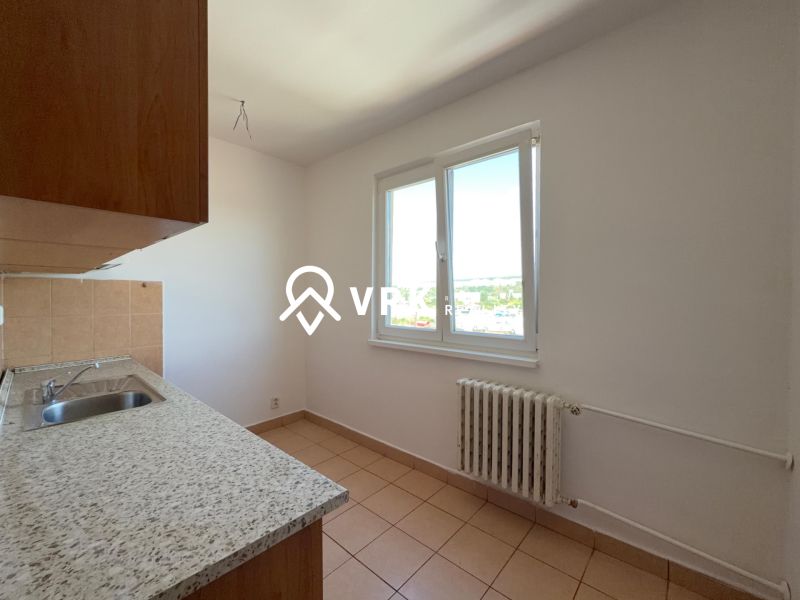 A kitchen in a 2-room apartment with a ceramic floor, simple cabinets, and a window with a view.