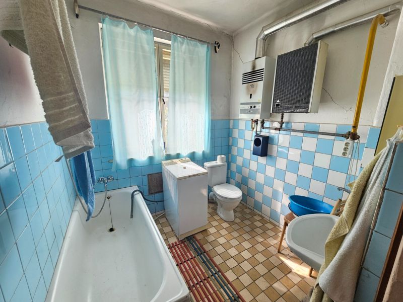Bathroom in a family house with blue tiles, a bathtub, and a sink.