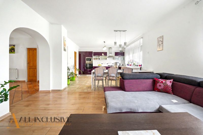 Interior of a family house with a kitchen, dining table, and wooden decor flooring.
