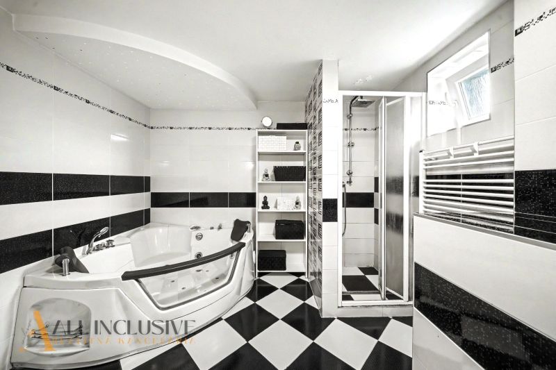 A bathroom in a family house with a hot tub, a shower, and black and white tiles.