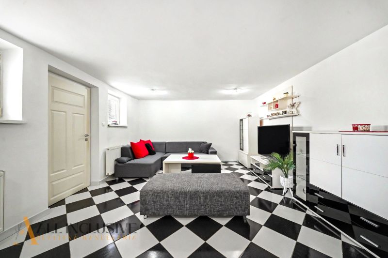 Living room in a family house with a black and white checkered floor and a gray sofa.