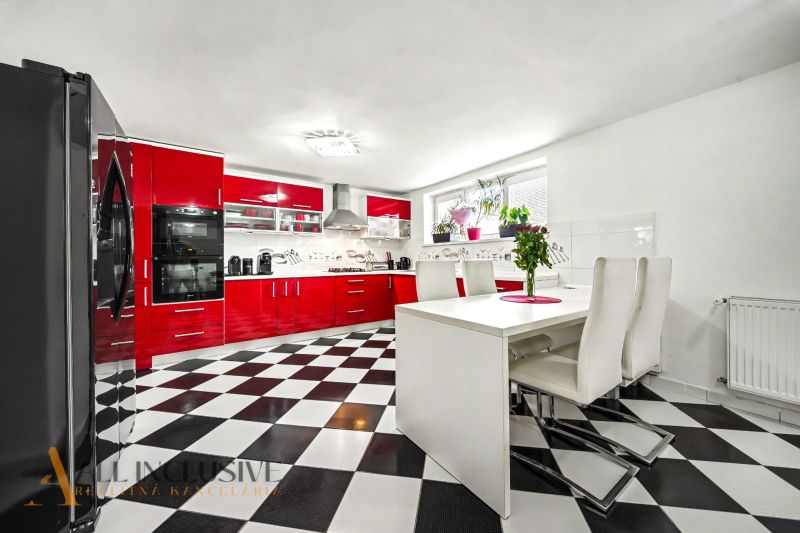 A kitchen in a family house with a black and white floor and red kitchen furniture.
