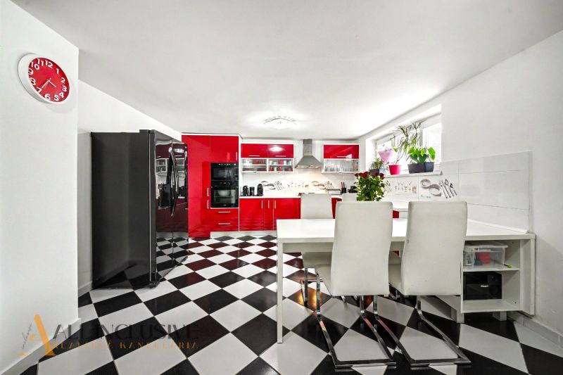 A kitchen with a black and white floor and red cabinets in a family house.