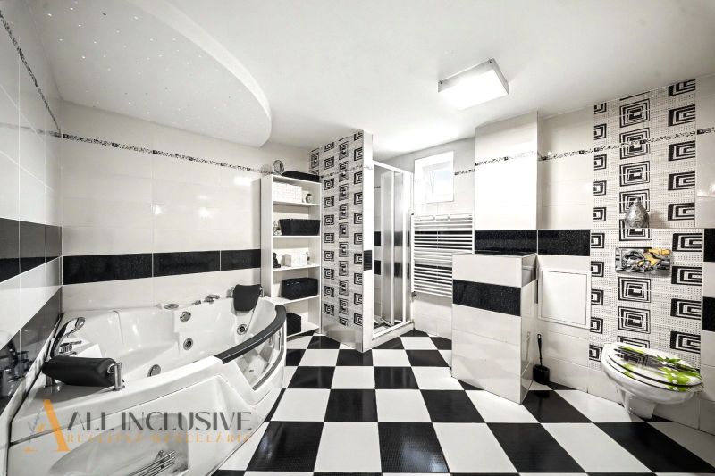 A black and white bathroom with a bathtub and a shower in a family house.