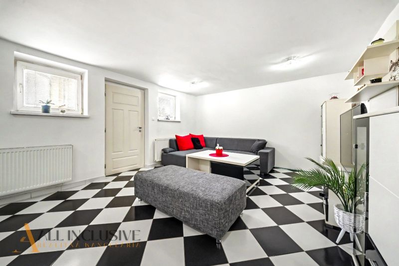 A living room in a family house with a checkered floor and gray seating furniture.