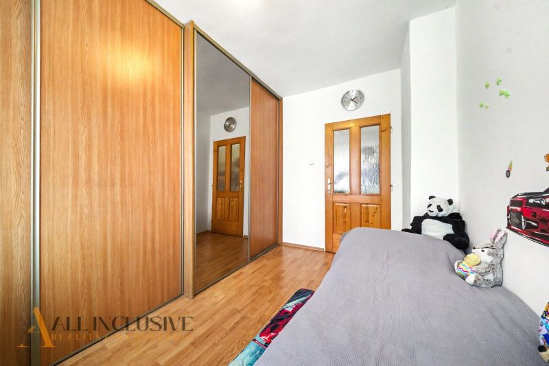 A bedroom in a family house with a wood-decorated floor and a large wardrobe with a mirror.