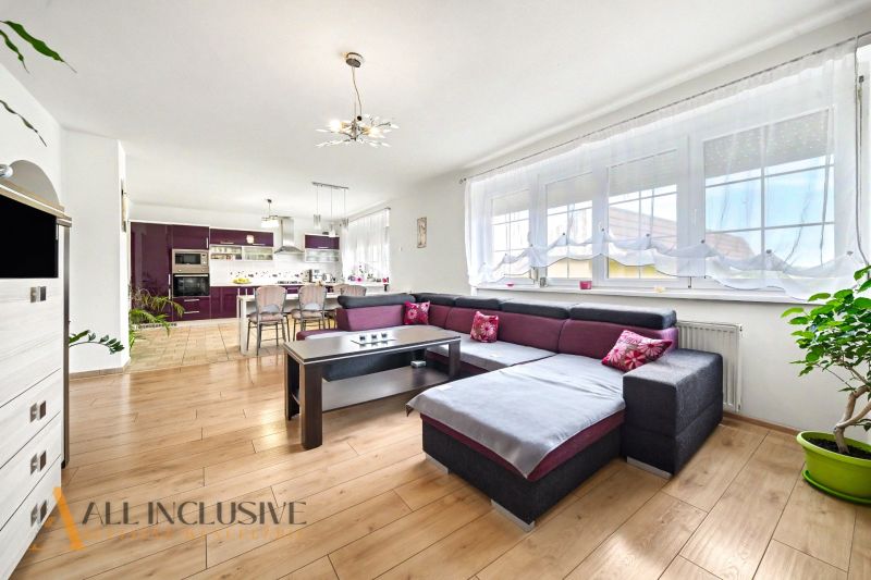 Living room in a family house with a spacious sofa and a wooden-patterned floor.