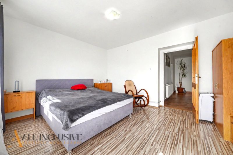 A bedroom in a family house with a comfortable bed, a rocking chair, and a floor with a wooden decor.