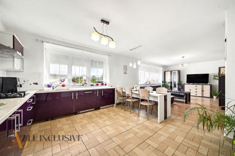 Spacious kitchen with dining area and wooden decor flooring in a family house.