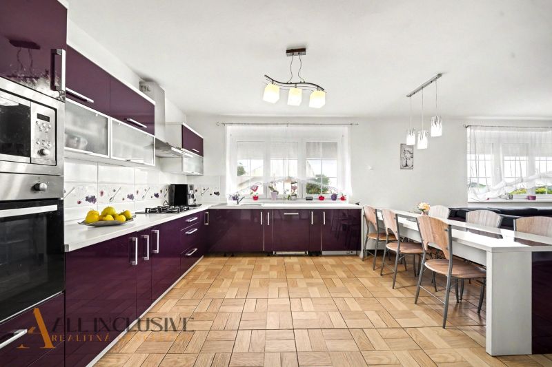 A kitchen in a family house with burgundy cabinets and a wooden decor floor.