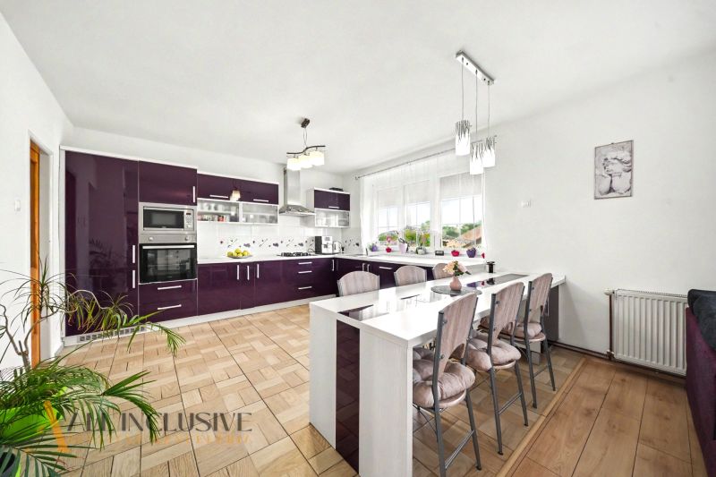 A kitchen in a family house with dark cabinets and a wood-patterned floor.