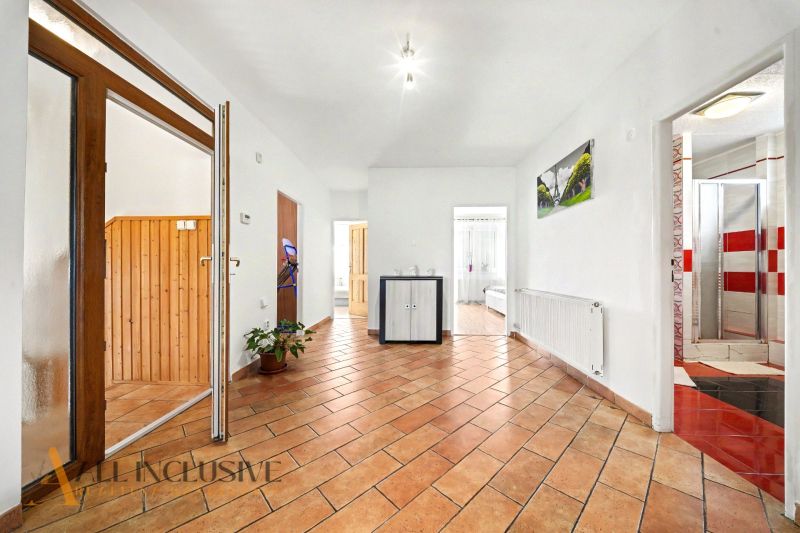 A spacious hallway with a tiled floor in a family house, featuring wooden interior elements.