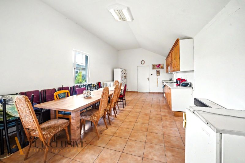 A spacious kitchen in a family house with a long dining set and tiles.