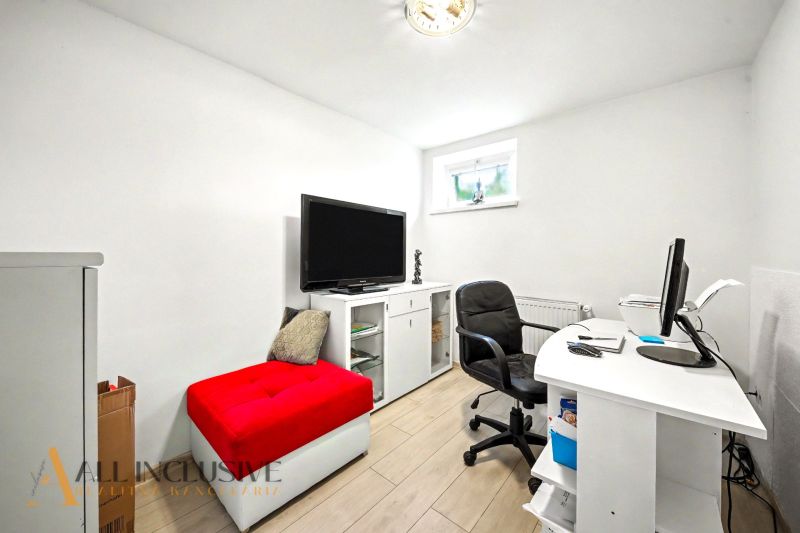 A study in a family house with white furniture and a red ottoman.