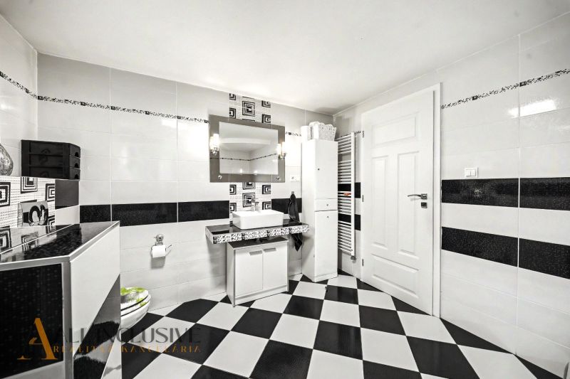 Bathroom in a family house with black and white tiles and a mirror above the sink.