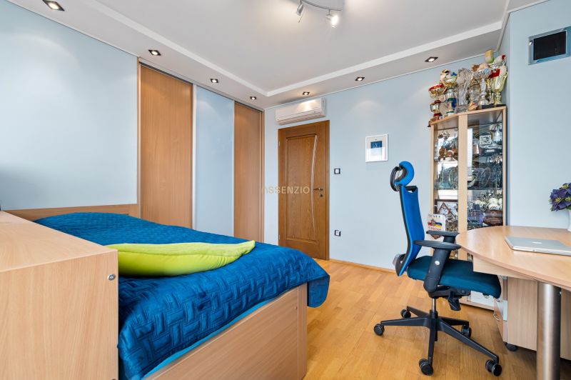 A bedroom in a family house with a wardrobe, a blue bed, trophies, and a wooden decor floor.