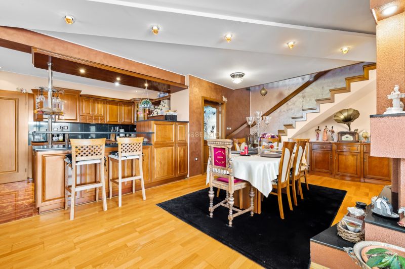 Interior of a family house with a kitchen, dining table, and wooden decor flooring.