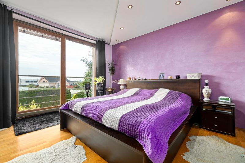 Stylish bedroom with a purple wall and a view, wooden decor flooring.