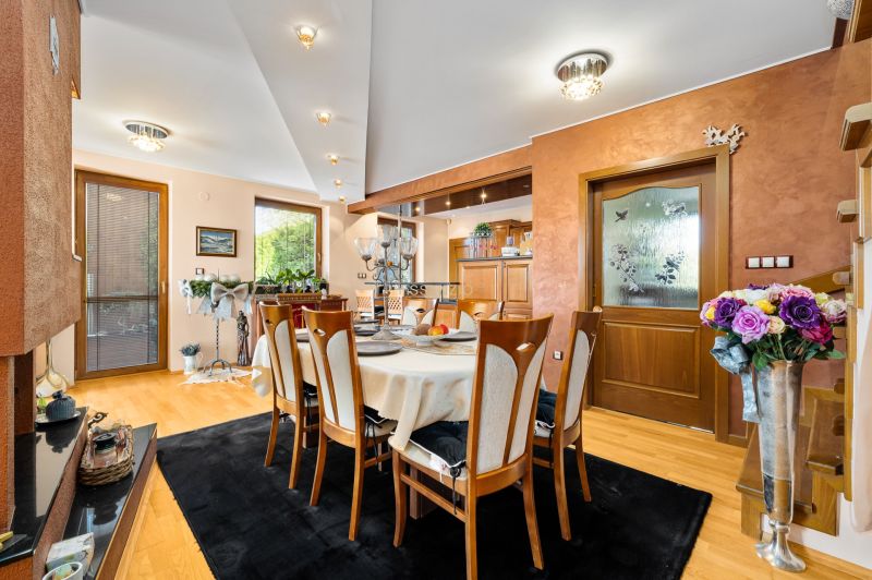 Dining room in a family house with a wooden decor floor and decorative flowers.