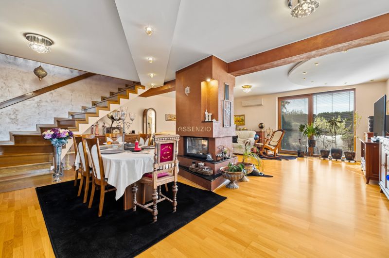 A family house with a dining table, fireplace, wooden stairs, and a floor with a wooden decor.