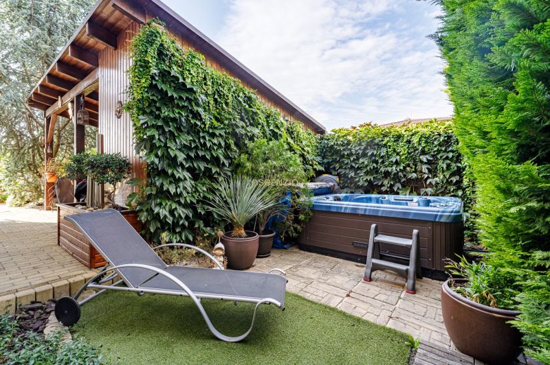 A family house garden with a deck chair, hot tub, and climbing plants on Majerská in Nová Dedinka.