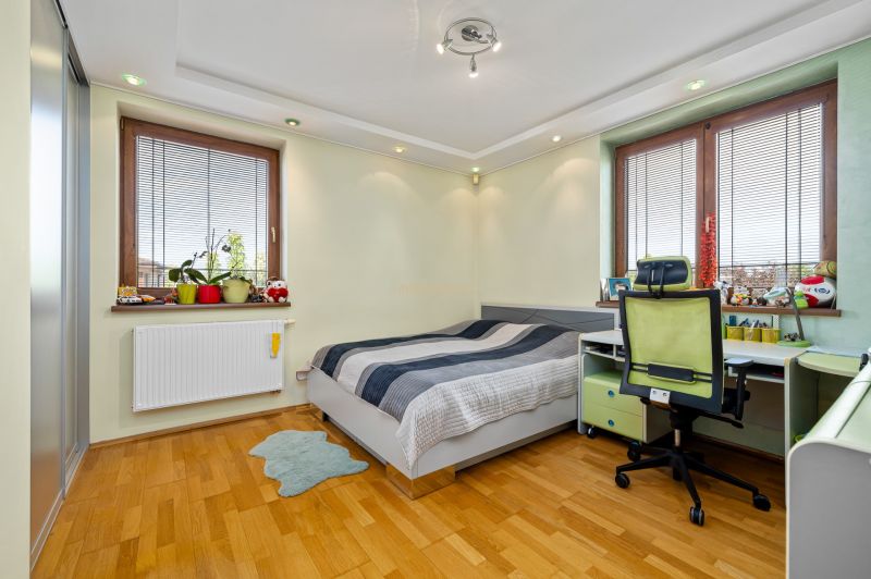 A children's room in a family house with a bed, a desk, and a floor with a wooden decor.