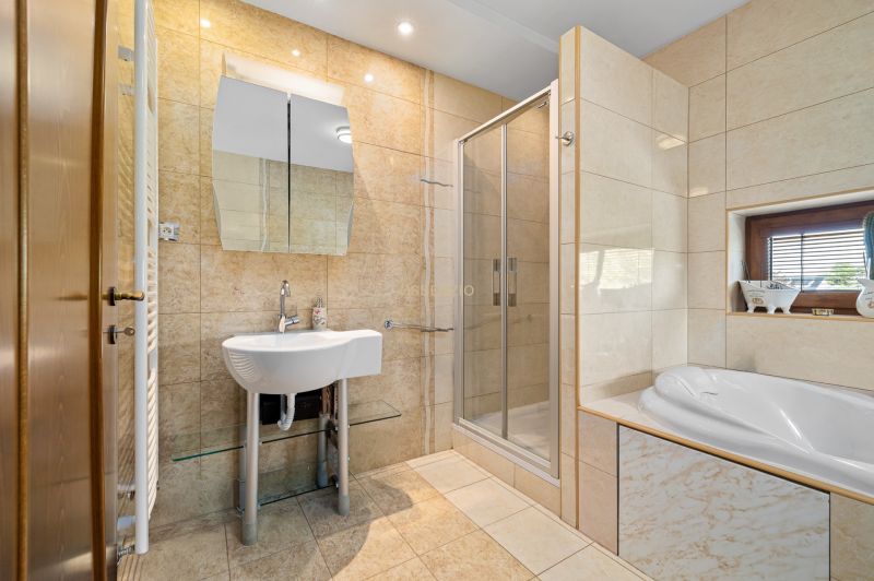 Bathroom with a bathtub, shower, and sink in a family house.