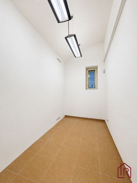 White walls, small room, ceiling lights, tiles, offices.