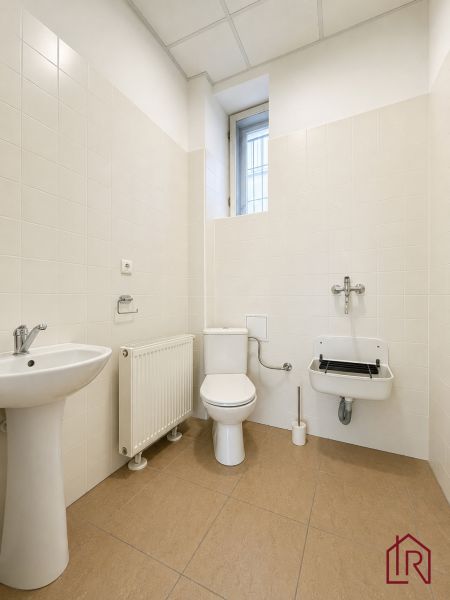 Office restroom with beige tiles and a sink.