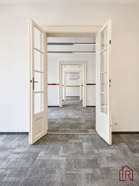 An open white door in an office with carpeted flooring.