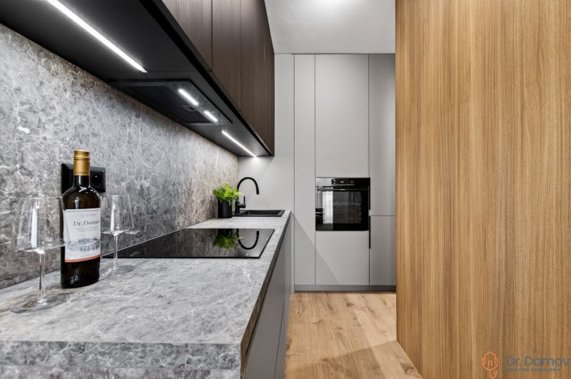 A kitchen in a 2-room apartment with a gray countertop and a wooden decor floor.