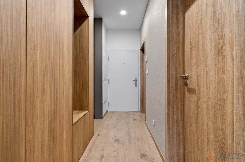 A hallway in a 2-room apartment with a wooden decor floor and wooden doors.
