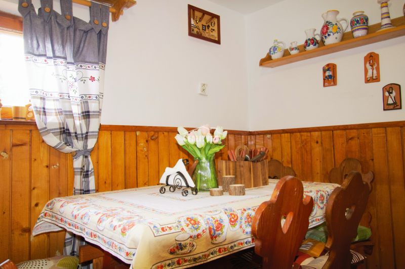 Interior of a cabin with a table, rustic decoration, and wooden wall paneling.