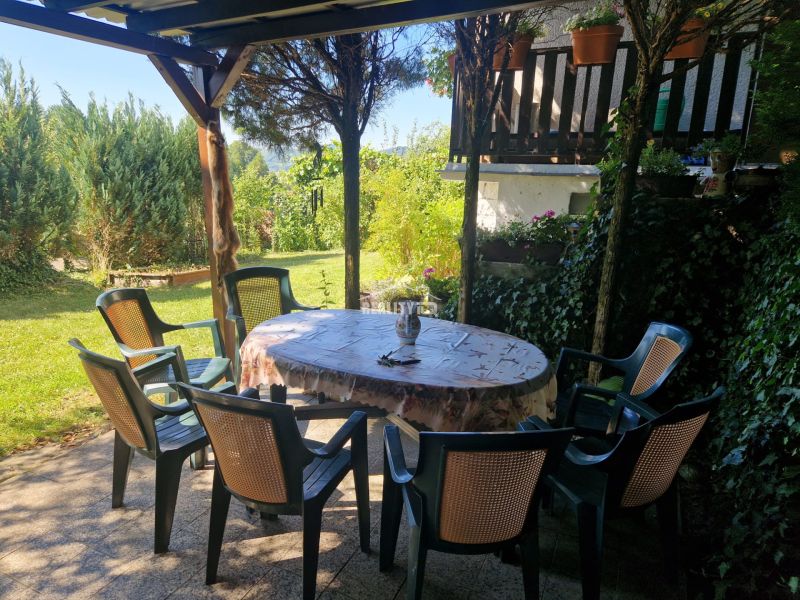 A garden with a terrace by the cottage in Žilina, plastic chairs around the table.