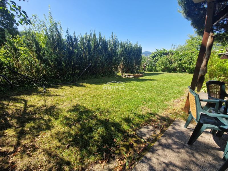 Garden space in Žilina near the cottage with chairs and greenery, surrounded by trees.