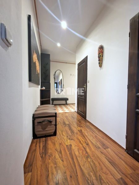 A hallway of a 3-room apartment with a wooden decor floor and wall decorations.