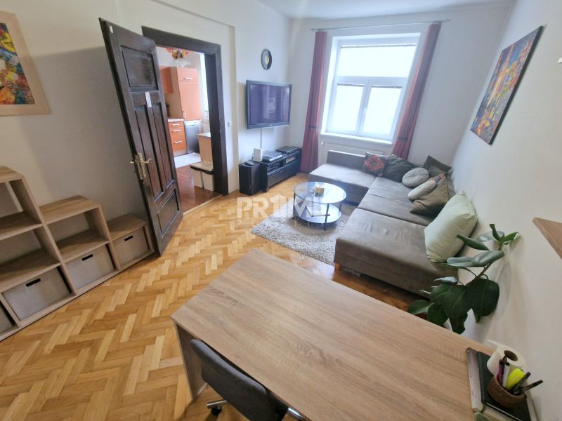 The living room in the three-room apartment features a comfortable sofa and a floor with a wooden design.