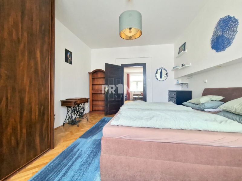 Bedroom in a 3-room apartment with a wooden decor floor, a double bed, and furniture.