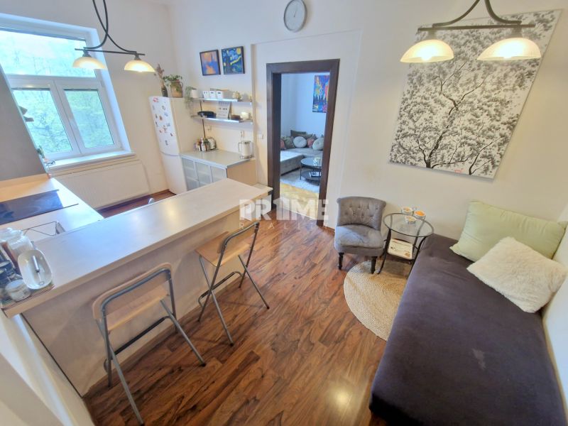 A kitchen in a 3-room apartment with a bar counter and a wooden decor floor.