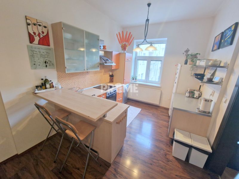 A kitchen in a 3-room apartment with a bar counter, shelves, and a floor with a wooden decor.
