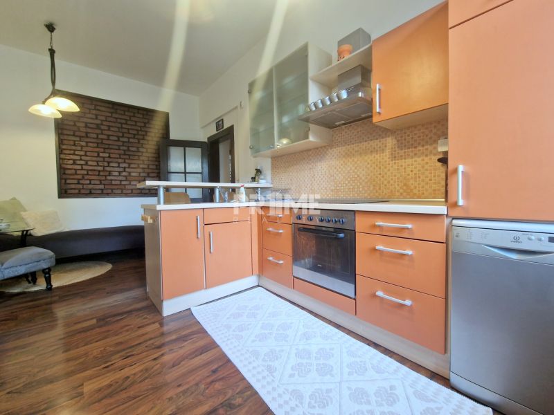A kitchen in a 3-room apartment with a wooden decor floor and a brick wall.