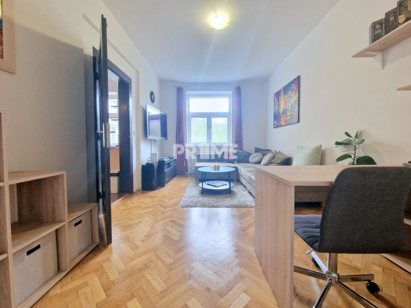 Living room with wood-patterned flooring, a sofa, and a desk in a 3-room apartment.